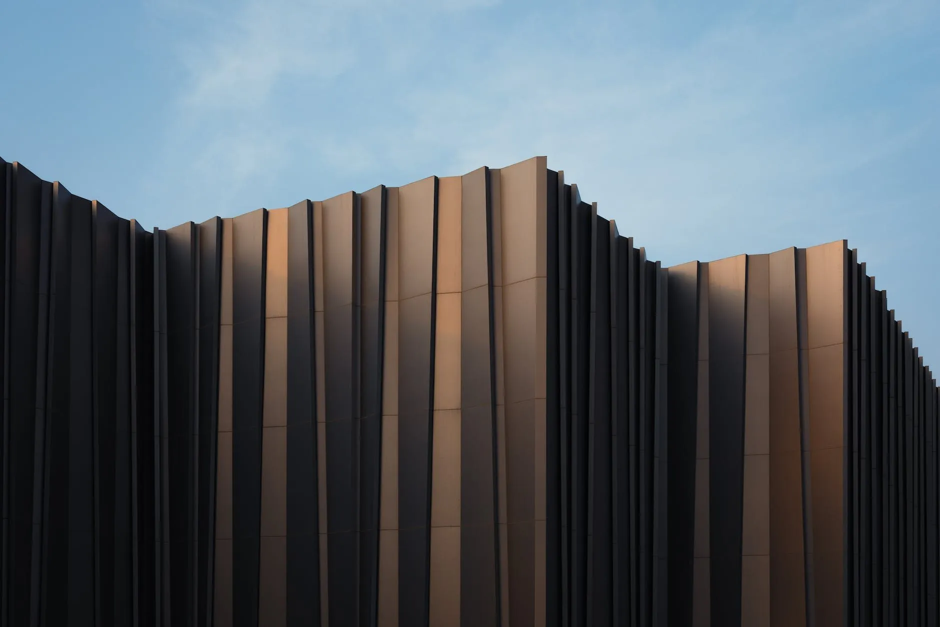 Folded bronze aluminium facade under a blue sky