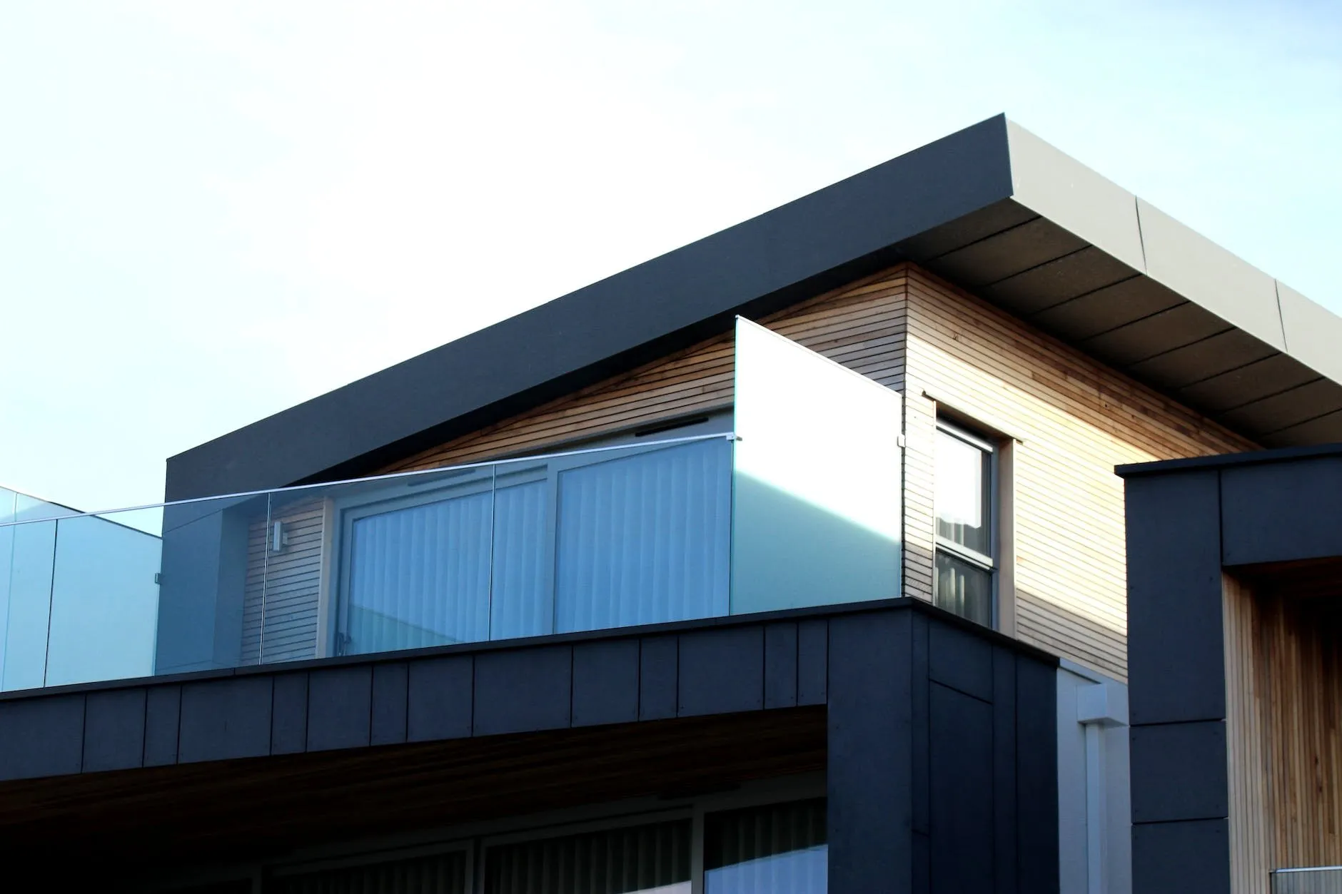 Timber-clad house with large windows and a dark cantilevered roof